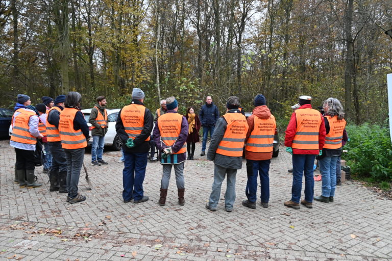 Alle vrijwilligers in een kring met een oranje hesje aan.